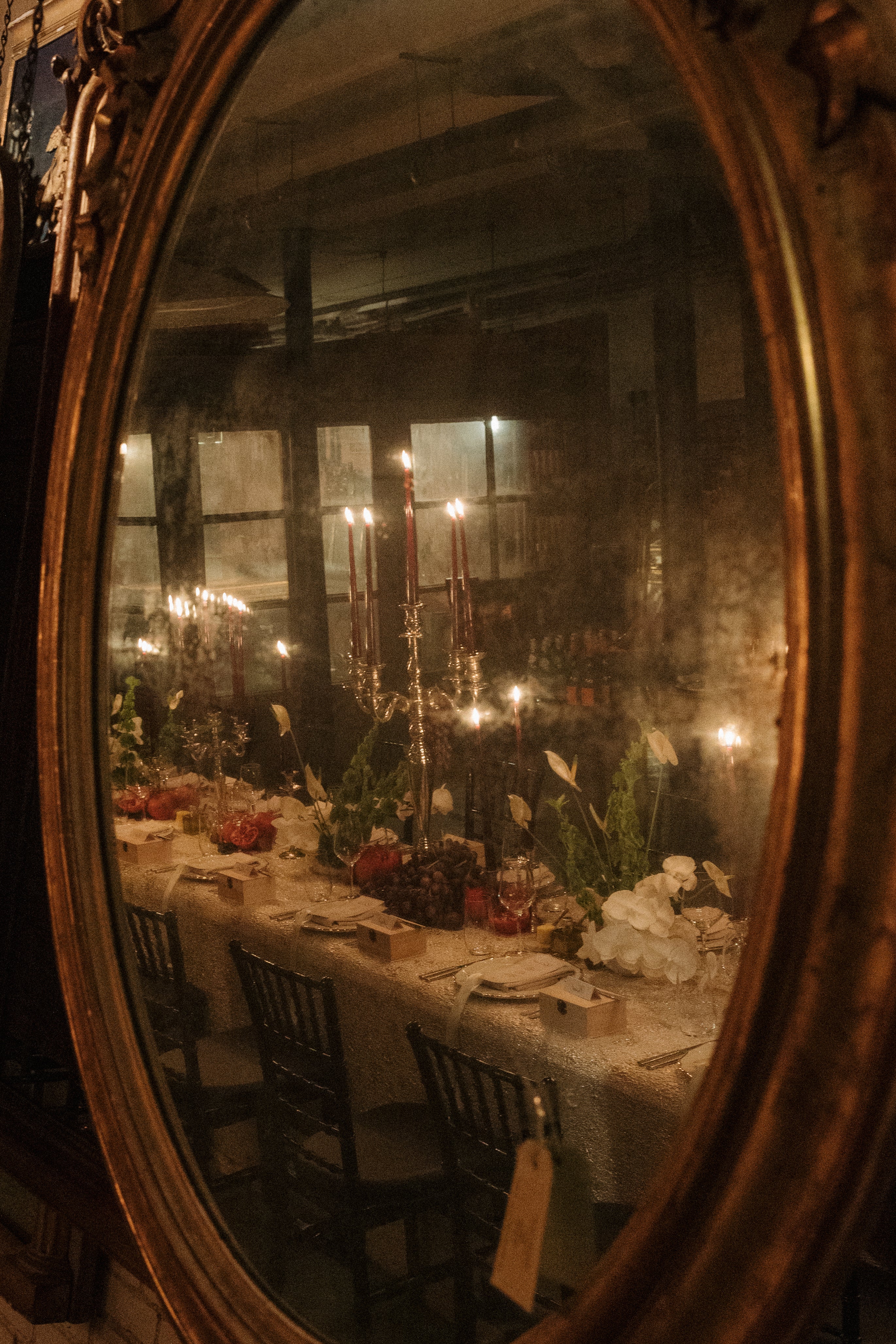 old antique mirror reflecting the elegant styled table setting with long candles.