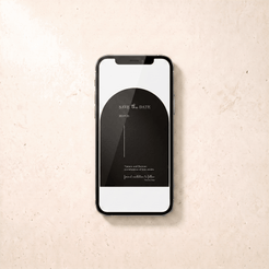 A black smartphone lying on a light beige textured surface, displaying a black minimalist 'Save the Date' card design on its screen.