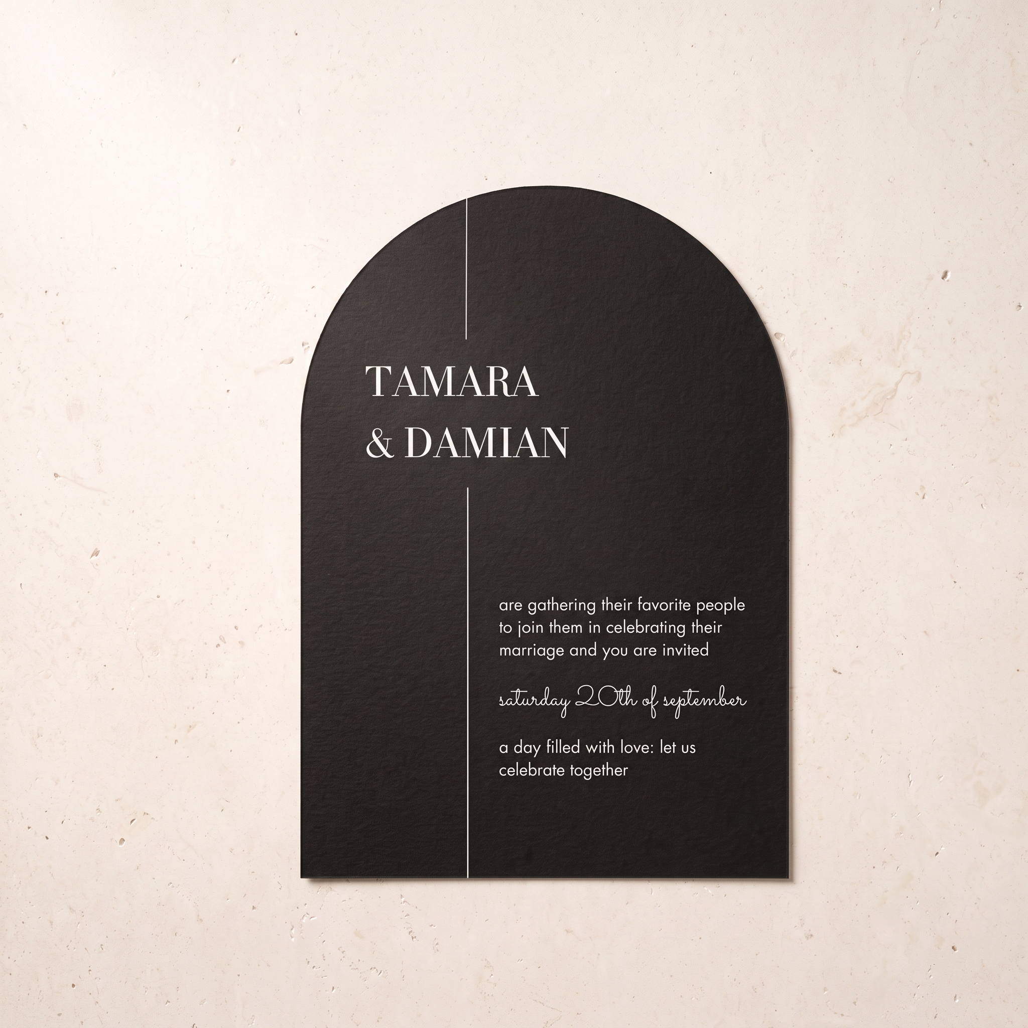 A black arched wedding invitation card with elegant white typography, displayed flat against a textured beige background.