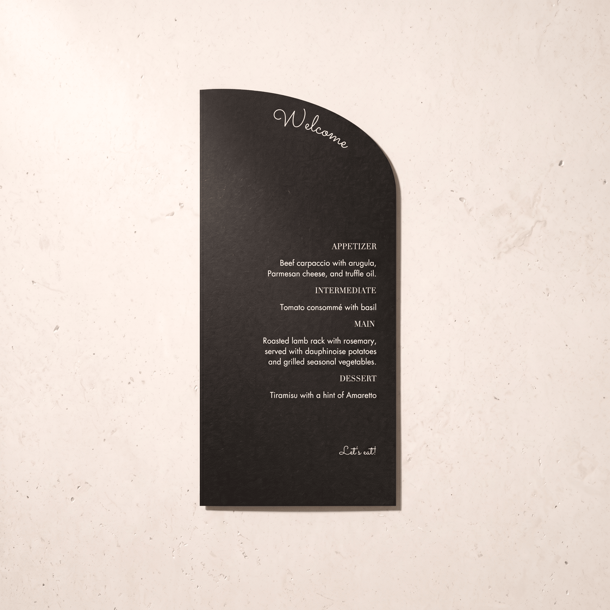 A black arched welcome placemat with white printed text, displayed flat against a textured off-white background.