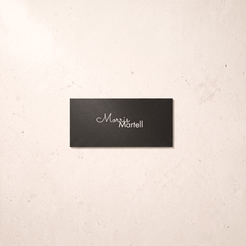 A rectangular black plaque with the name 'Morris Martell' in white script and serif lettering, mounted on a light beige textured wall.