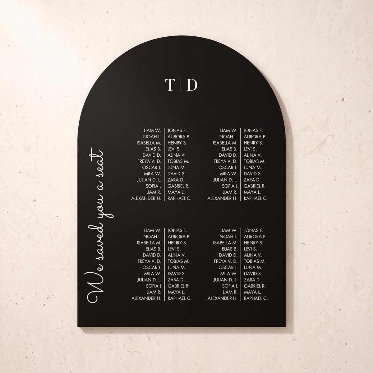 A black arched wedding seating chart plaque with white printed names and the text 'We saved you a seat' and 'TOD', shown on a light beige textured background.