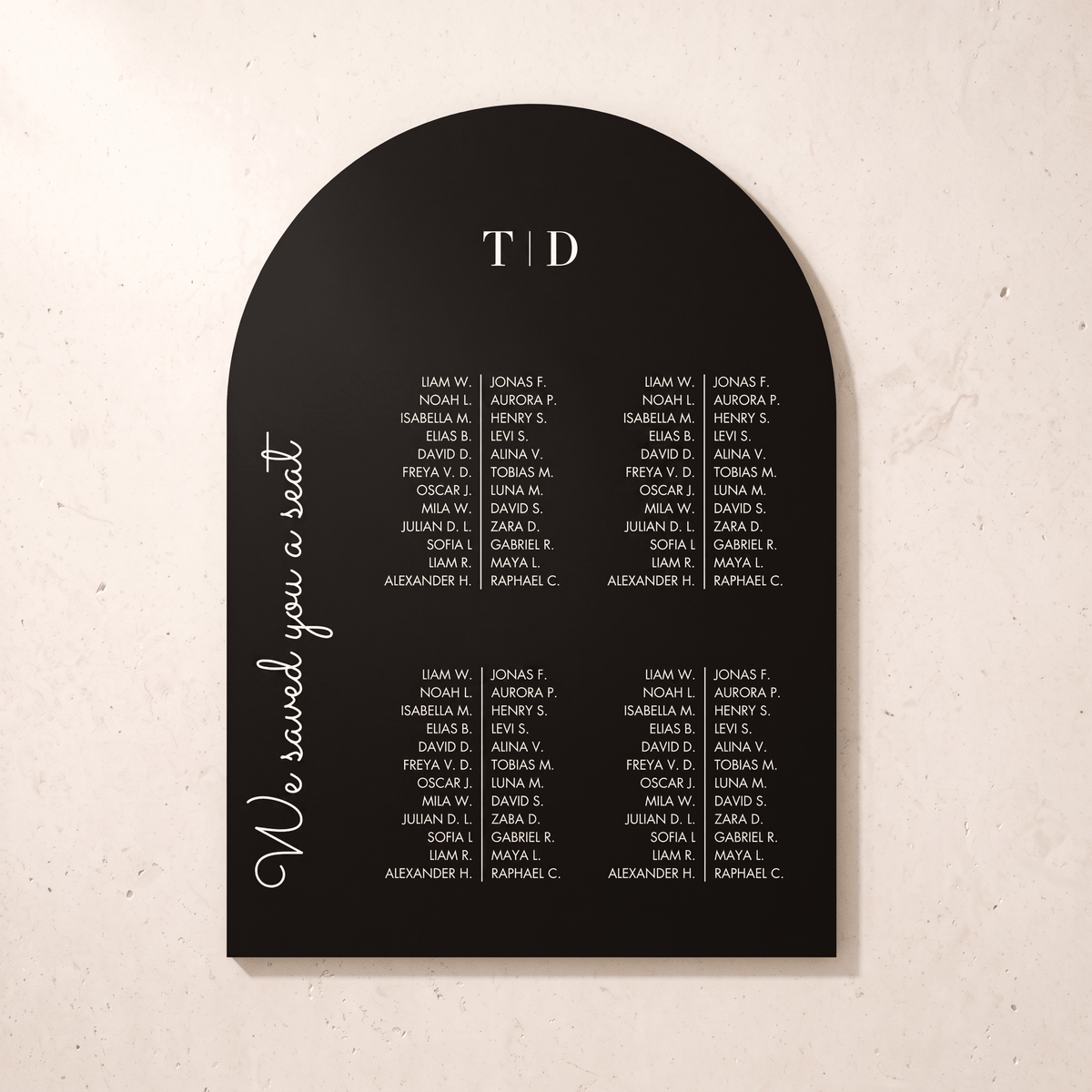 A black arched wedding seating chart plaque with white printed names and the text 'We saved you a seat' and 'TOD', shown on a light beige textured background.