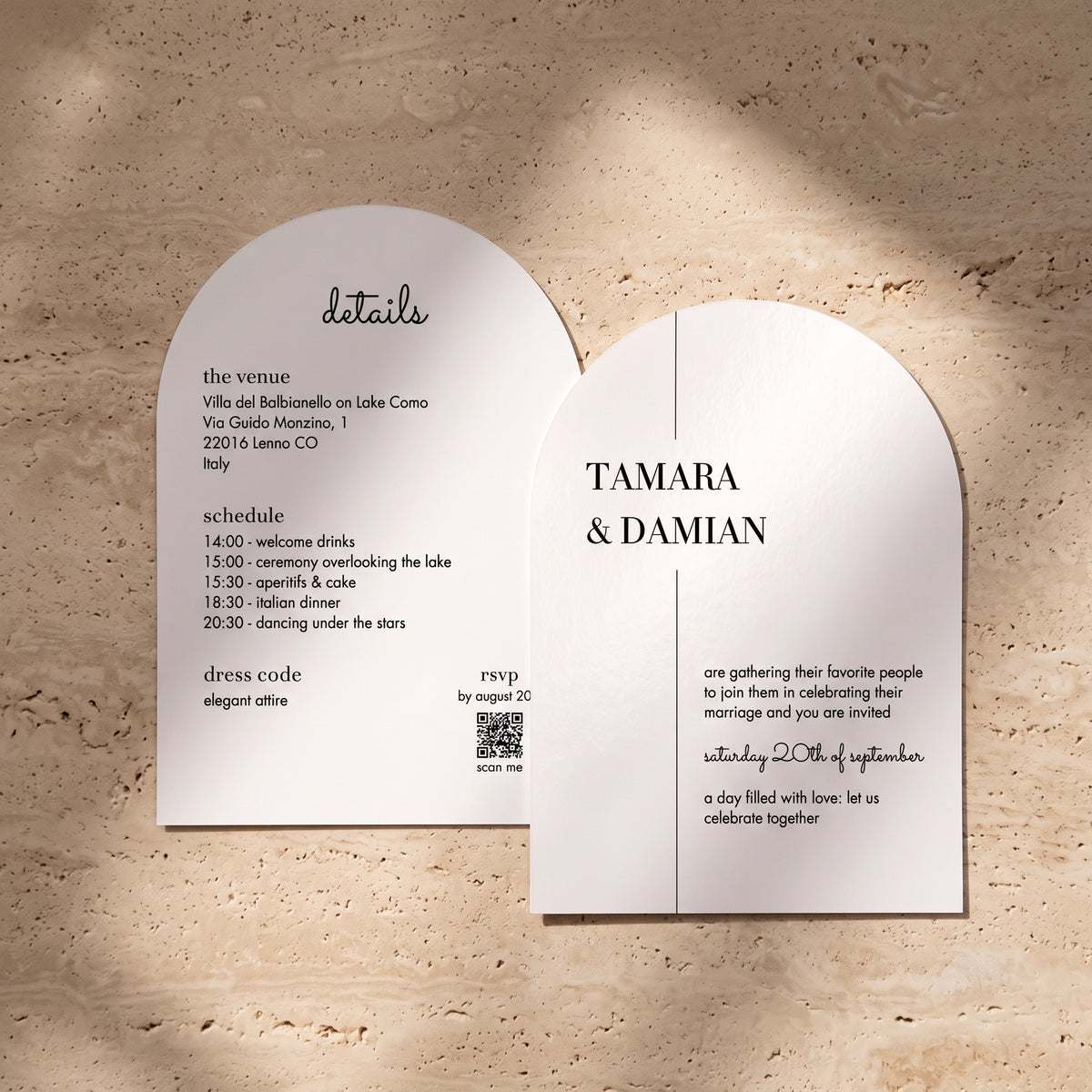 Two arched white invitation cards with black text, displayed on a textured beige stone surface with soft shadows.