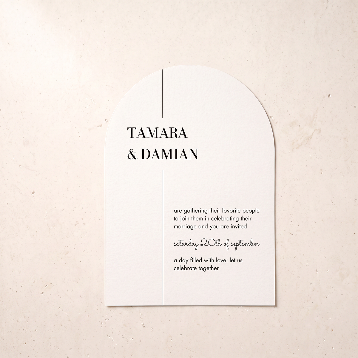 A minimalist arched wedding invitation card with black text on a warm off-white background, photographed flat against a light beige textured surface.
