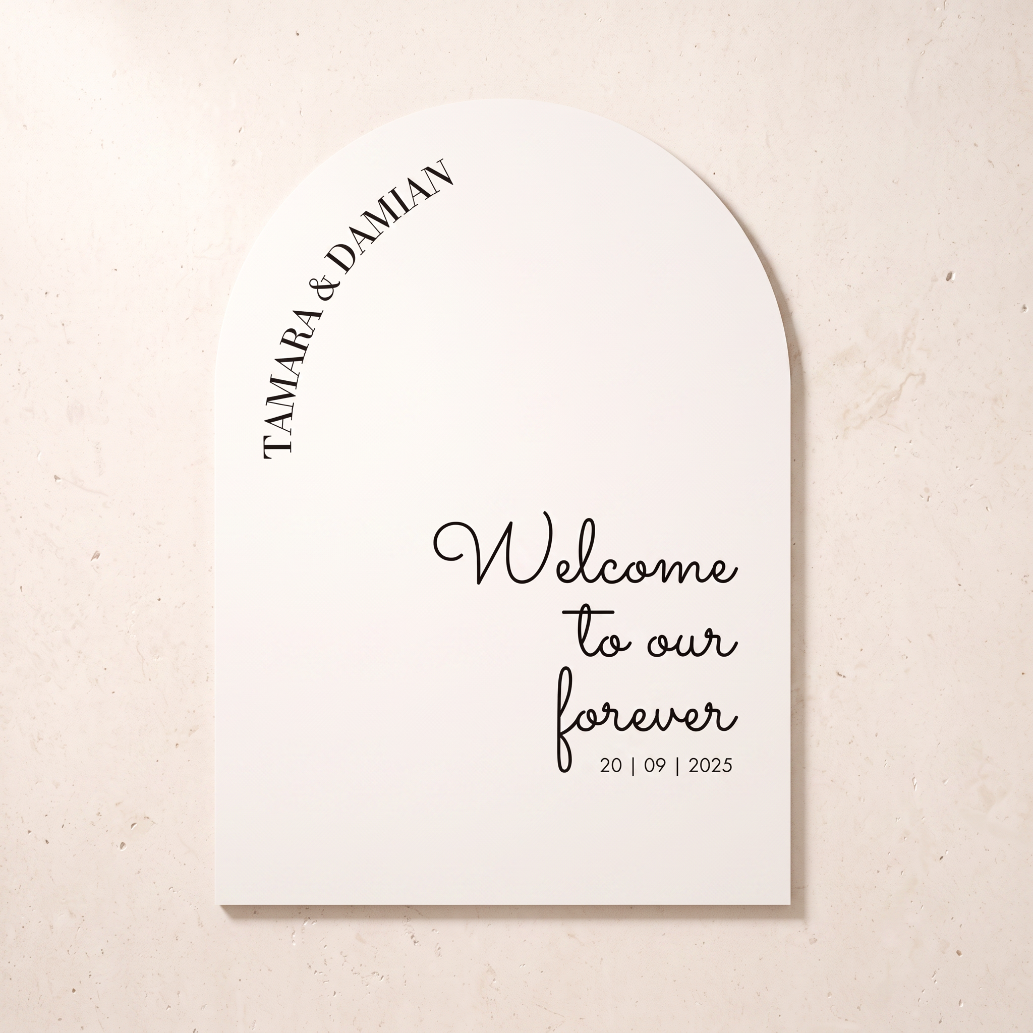 A personalized tombstone-shaped wedding sign with an arched top, printed with the names 'TAMARA & DAMIAN' and the phrase 'Welcome to our forever 20 | 09 | 2025' in black text on a warm off-white background, shown against a light beige textured wall.