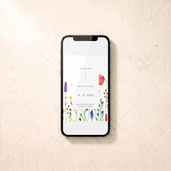 A black smartphone lying on a light beige textured surface, displaying a wedding save-the-date card design with floral illustrations and the names 'Higuchi & Steven' and the date '16 11 2025'.