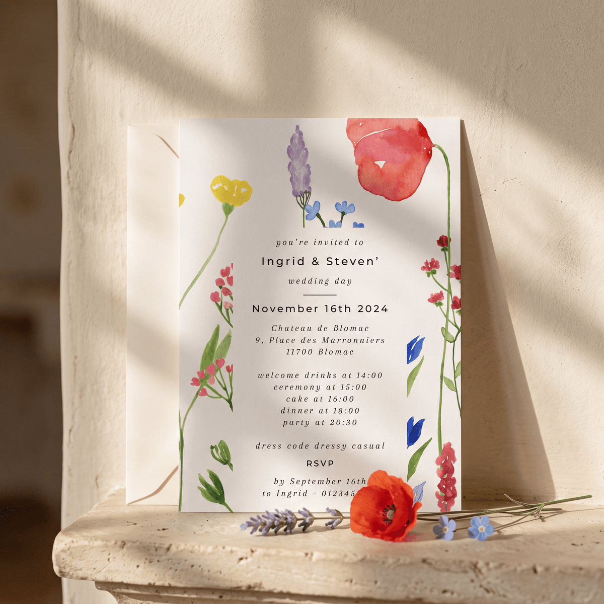 A floral wedding invitation card with elegant black typography, styled on a rustic stone ledge with soft natural shadows. The card features delicate watercolor illustrations of red, pink, purple, and yellow wildflowers with green stems on a white background.
