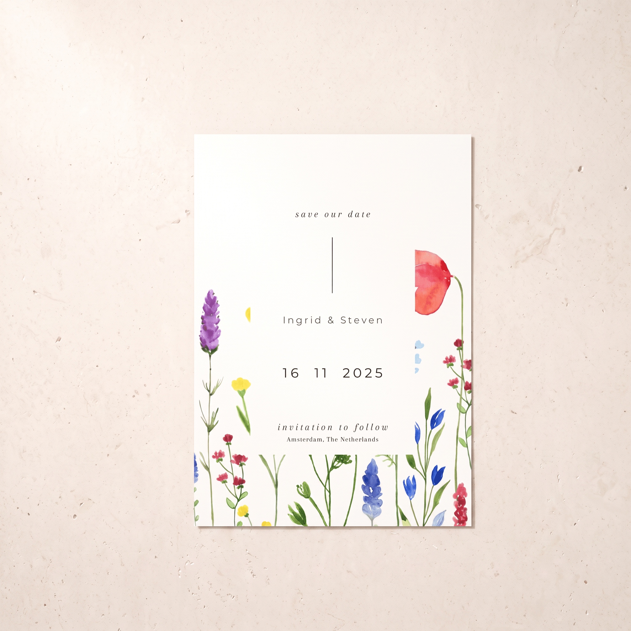 A vertical white save-the-date card with watercolor wildflower illustrations in red, purple, blue, yellow, and green, placed on a light beige textured surface.