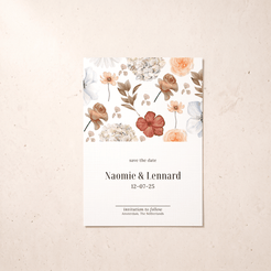 A vertical 'save the date' card with a watercolor floral design at the top and elegant black text below, displayed flat on a textured beige surface.