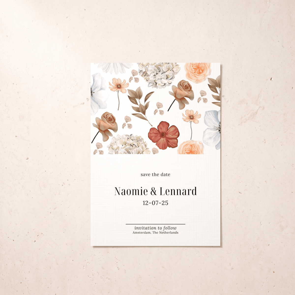 A vertical 'save the date' card with a watercolor floral design at the top and elegant black text below, displayed flat on a textured beige surface.