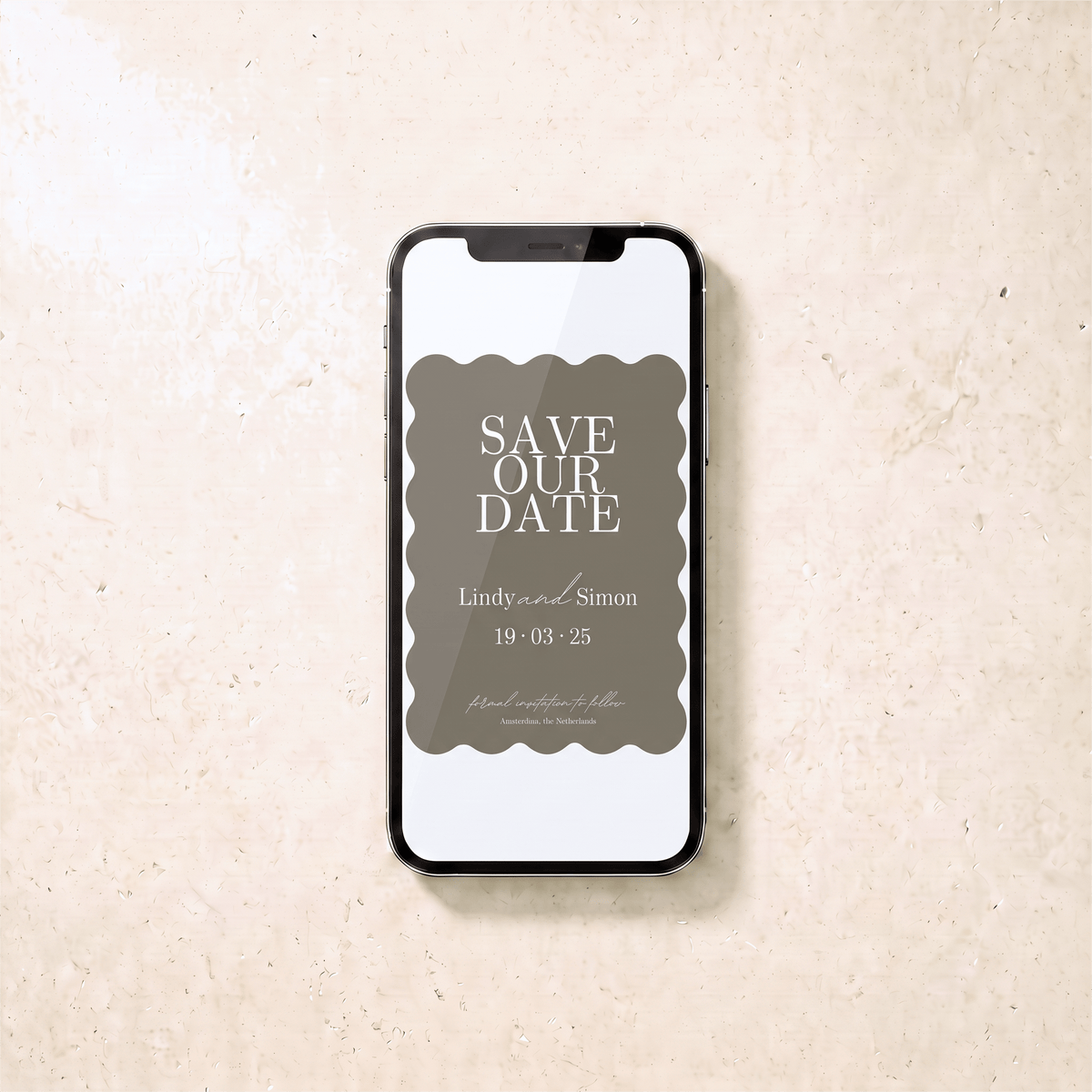 A smartphone centered on a light beige stone-like surface, displaying a 'Save Our Date' invitation card design with a muted taupe background and white text.