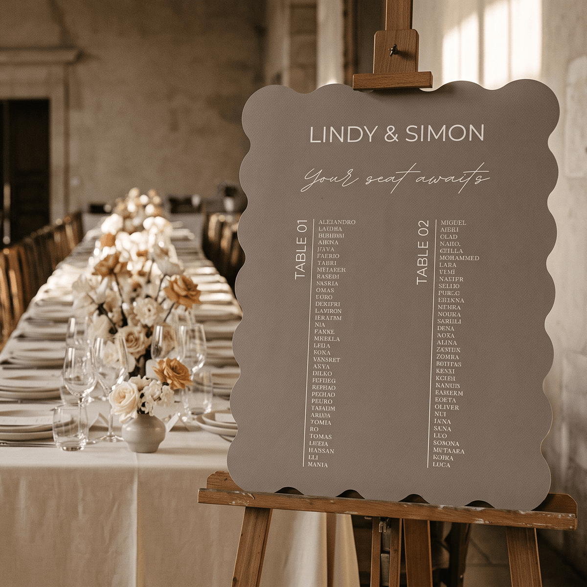 A scalloped gray wedding seat chart sign on an easel, displayed in a beautifully decorated wedding reception hall with a long table set in the blurred background.