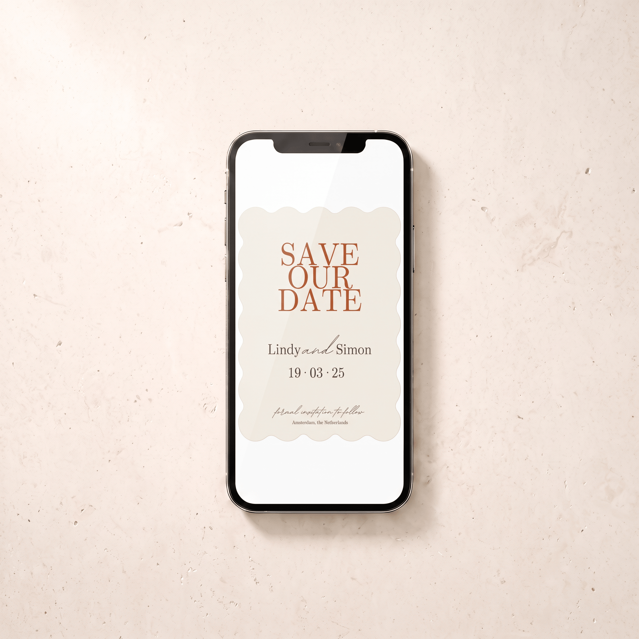 A smartphone centered on a light beige textured surface, displaying a wedding 'Save the Date' card design with peach lettering and scalloped cream borders.