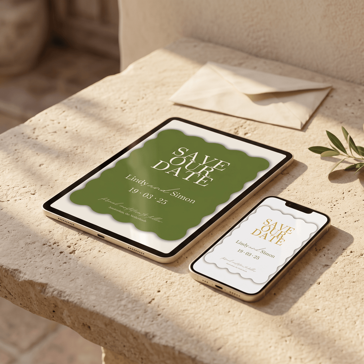 A styled flat-lay mockup of a digital 'Save the Date' invitation design shown on a tablet and smartphone, placed on a beige stone ledge next to a cream envelope and olive leaves.