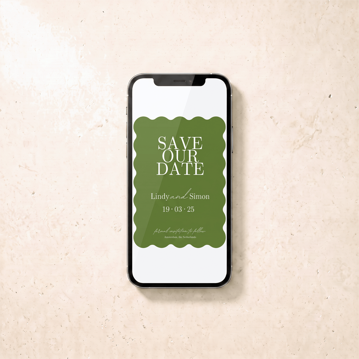 A smartphone lying on a light beige textured surface, displaying a green and white 'Save Our Date' card design.