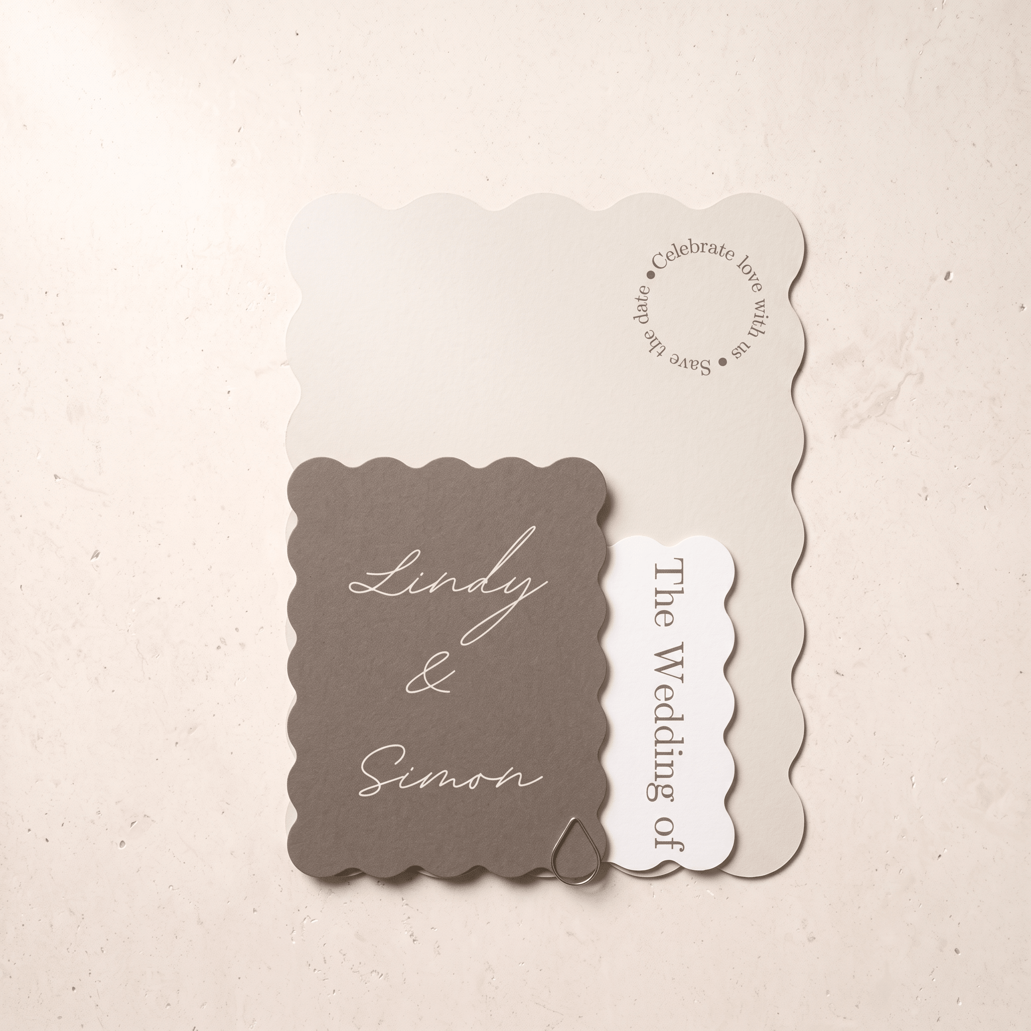 A wedding invitation suite featuring a taupe scalloped card with 'Lindy & Simon' in white script, layered over a cream card that reads 'Celebrate love with us' and a small white tag reading 'The Wedding of'.