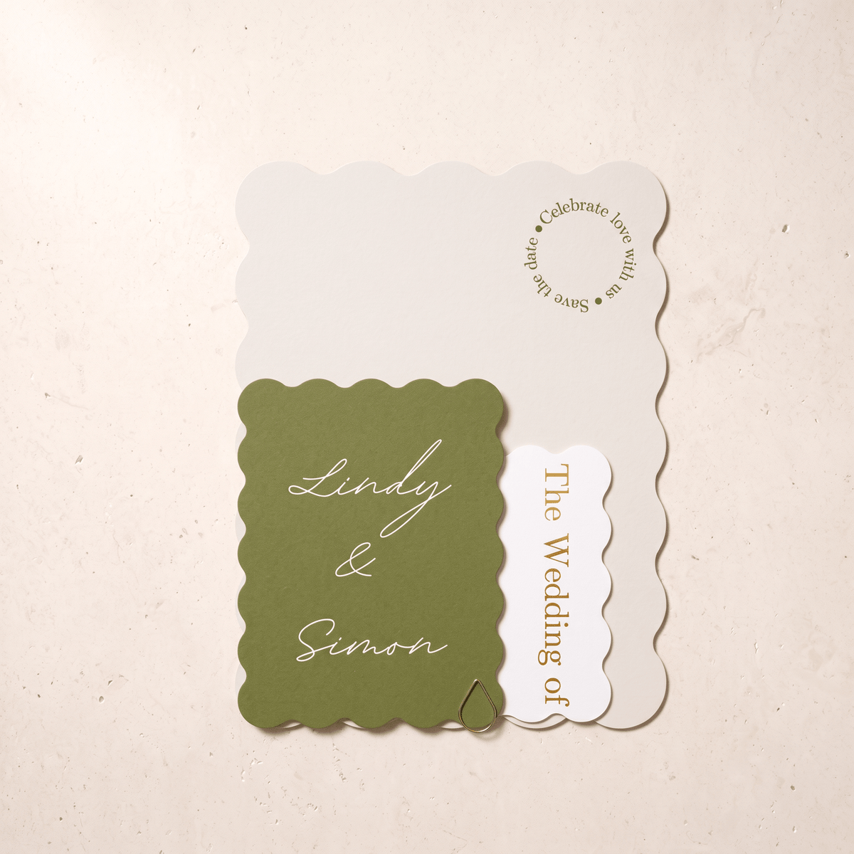 A wedding invitation suite featuring a scalloped olive green card with white script reading 'Lindy & Simon,' a white scalloped card with gold text reading 'The Wedding of,' and a larger off-white invitation background card with gold text, arranged on a light beige textured surface.