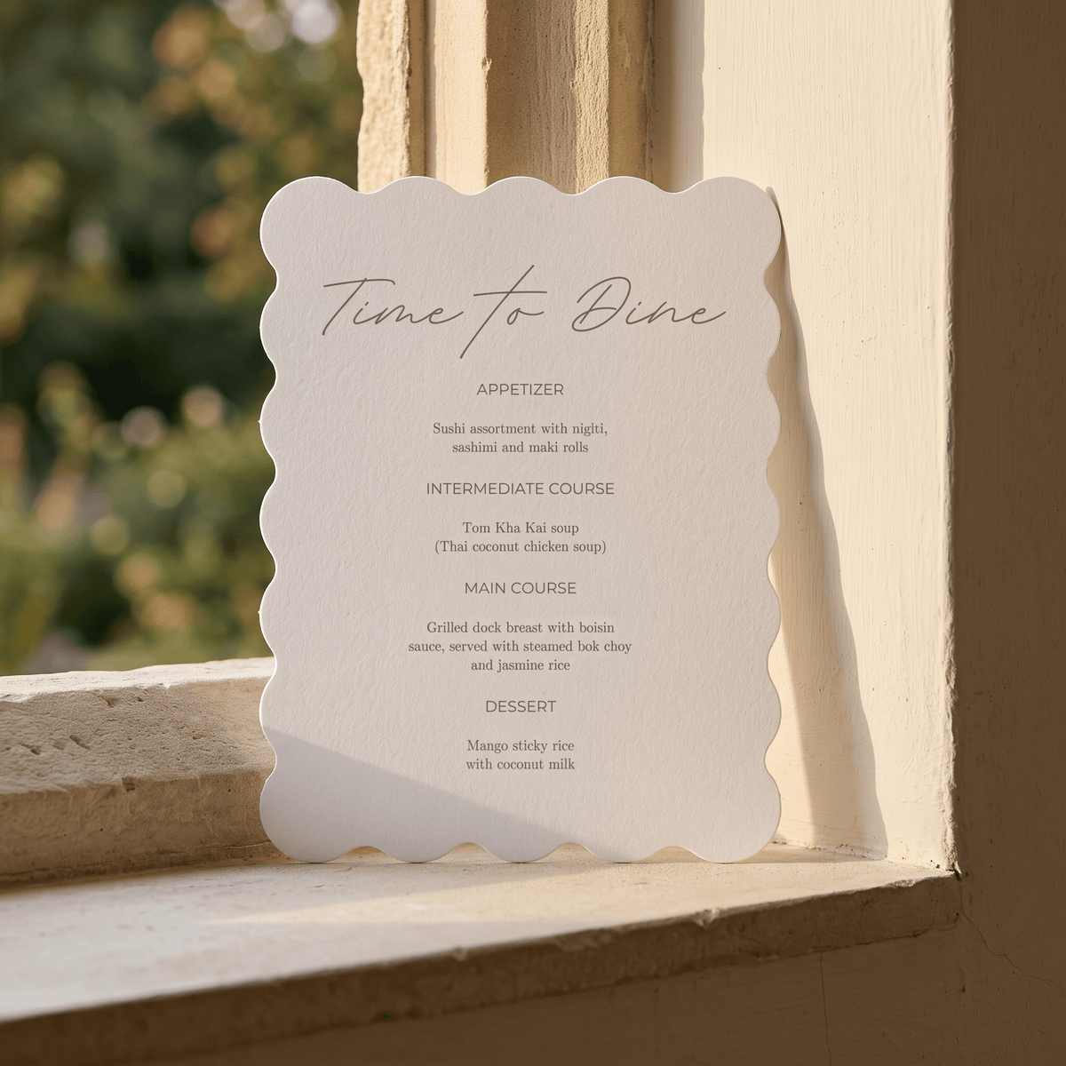 A scalloped-edge white paper menu card with elegant script reading 'Time to Dine' and course text below, leaning against a beige stone window ledge with blurred green foliage in the background.