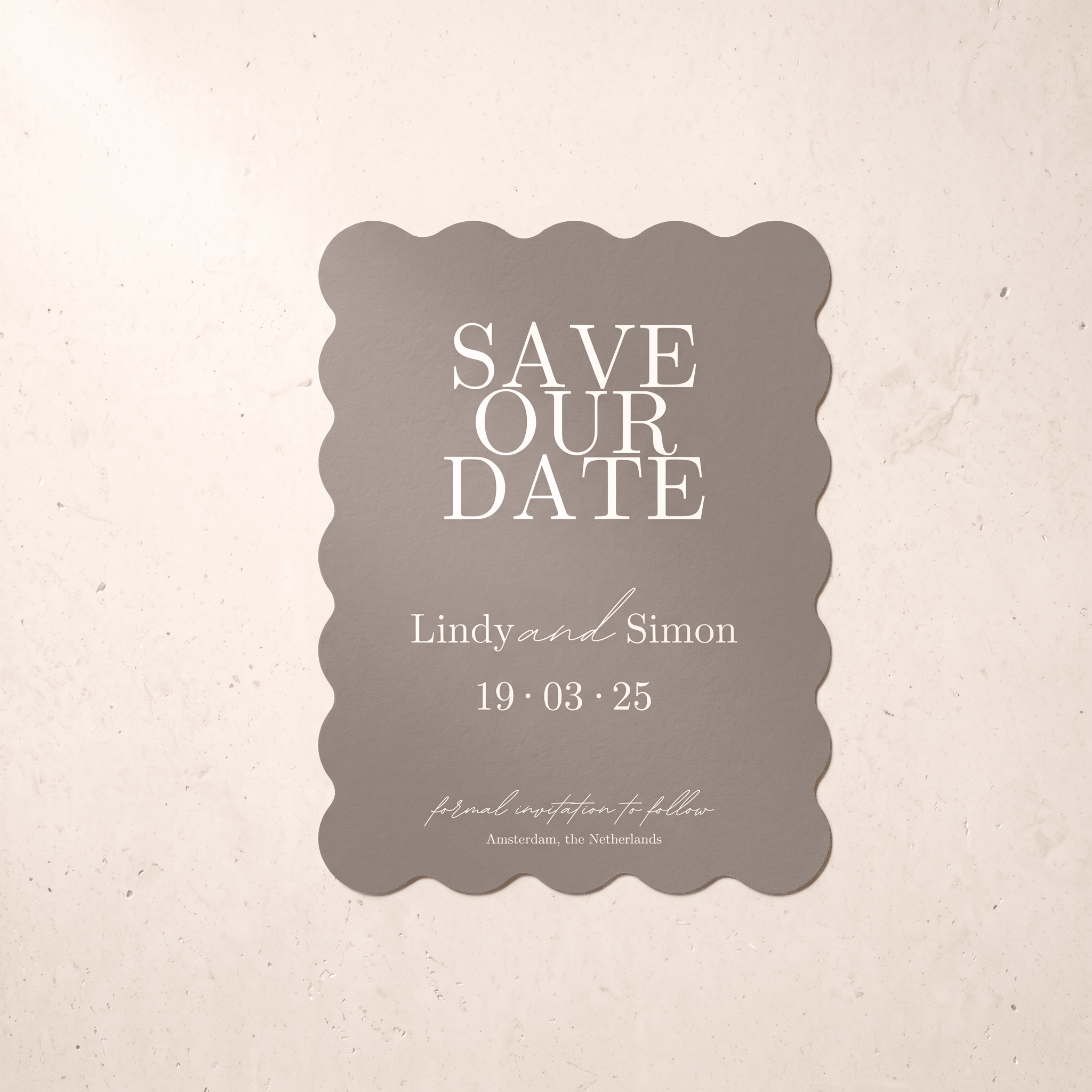 A scalloped rectangular save-the-date card in warm taupe with white text, centered on a light beige textured background.