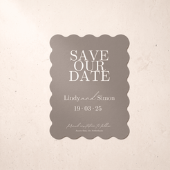 A scalloped rectangular save-the-date card in warm taupe with white text, centered on a light beige textured background.