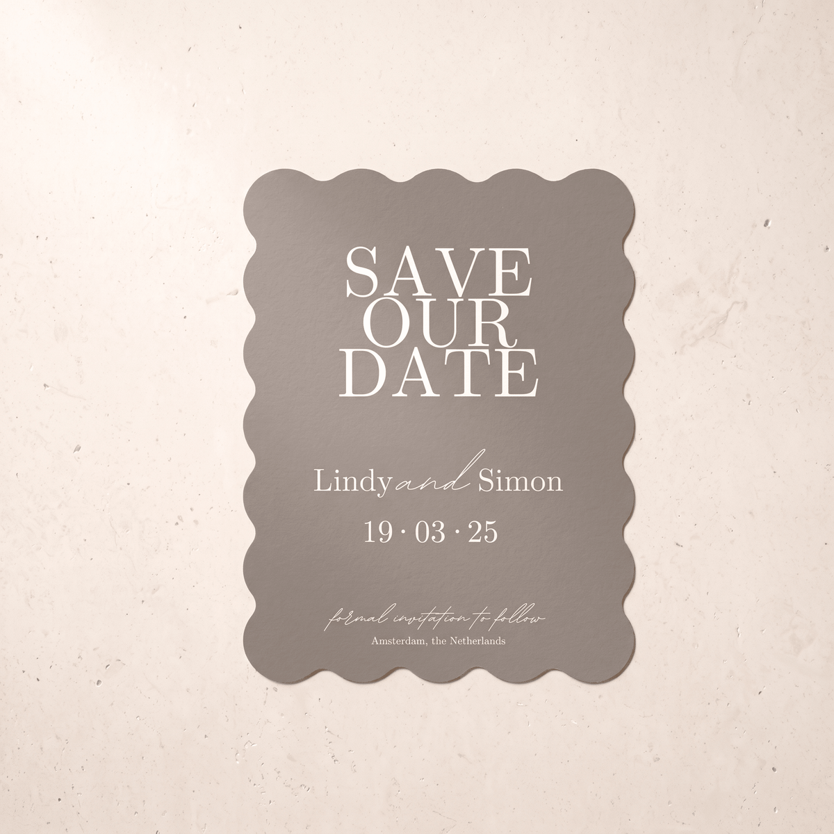 A scalloped rectangular save-the-date card in warm taupe with white text, centered on a light beige textured background.