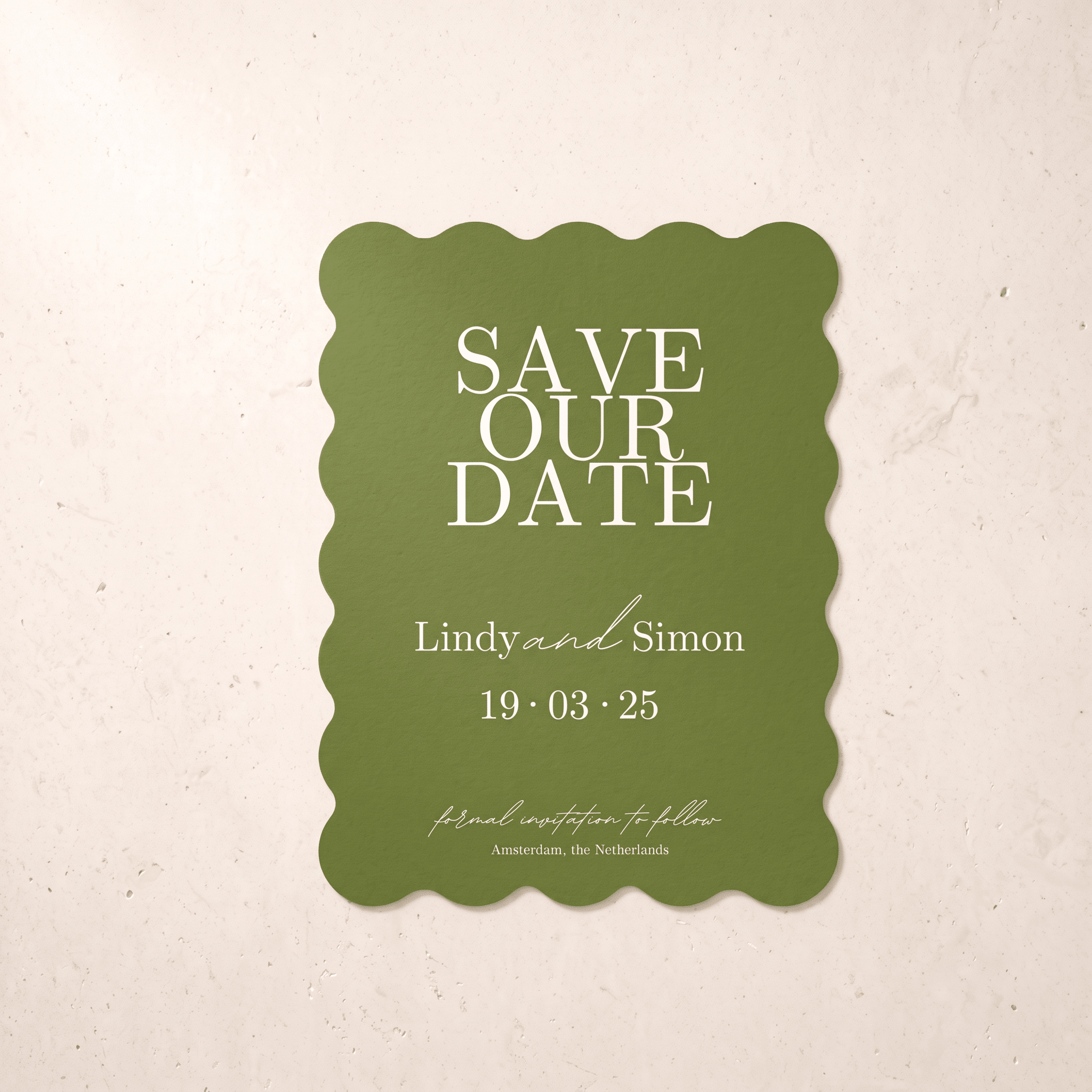 A green scalloped 'Save Our Date' card with white text, displayed against a textured beige background.