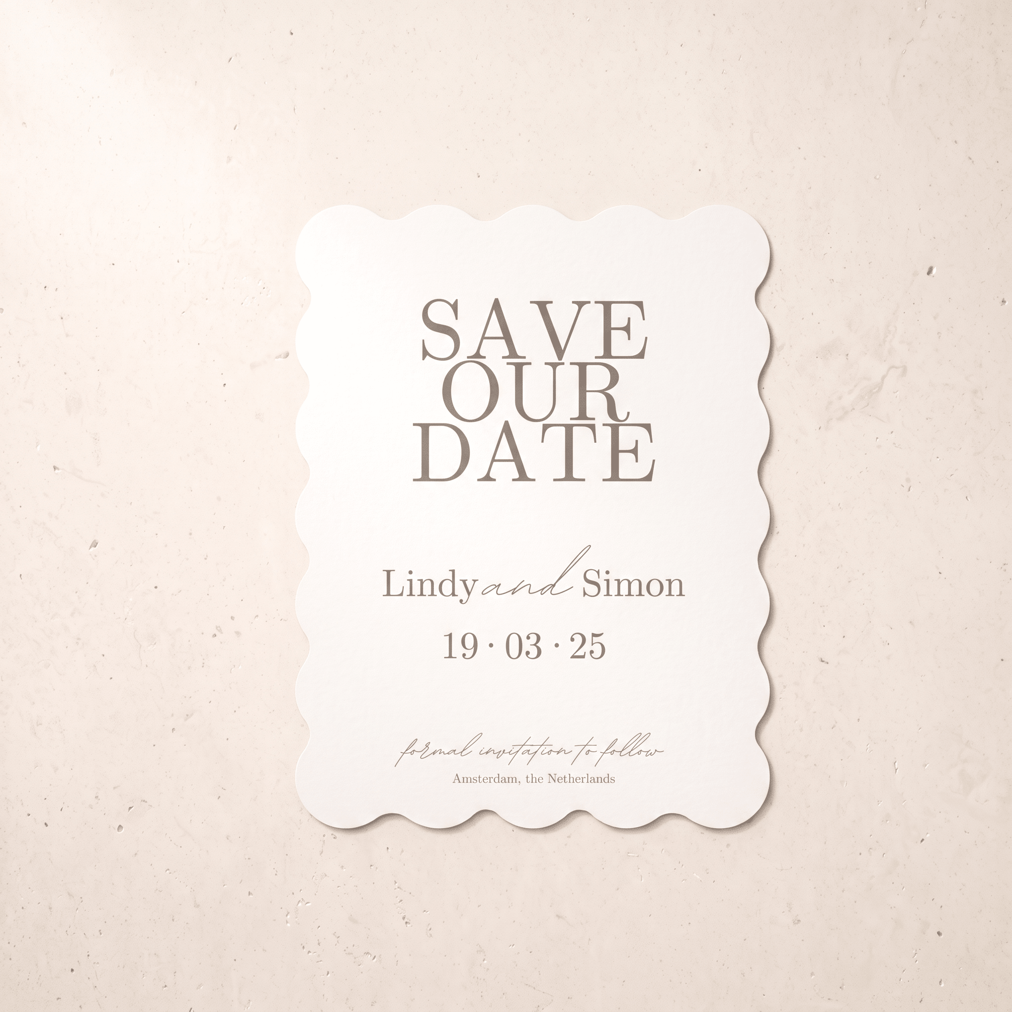 A scalloped white 'Save Our Date' card with gray text, displayed flat on a textured beige background.