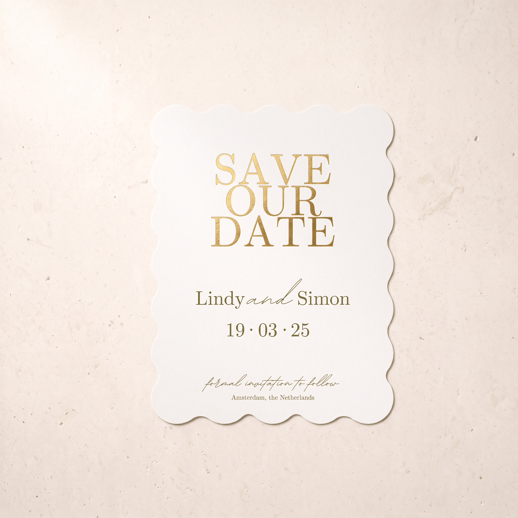 A scalloped white 'Save Our Date' card with elegant gold foil lettering, displayed flat against a textured beige background.