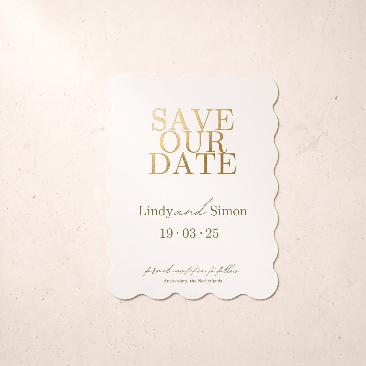 A scalloped white 'Save Our Date' card with elegant gold foil lettering, displayed flat against a textured beige background.