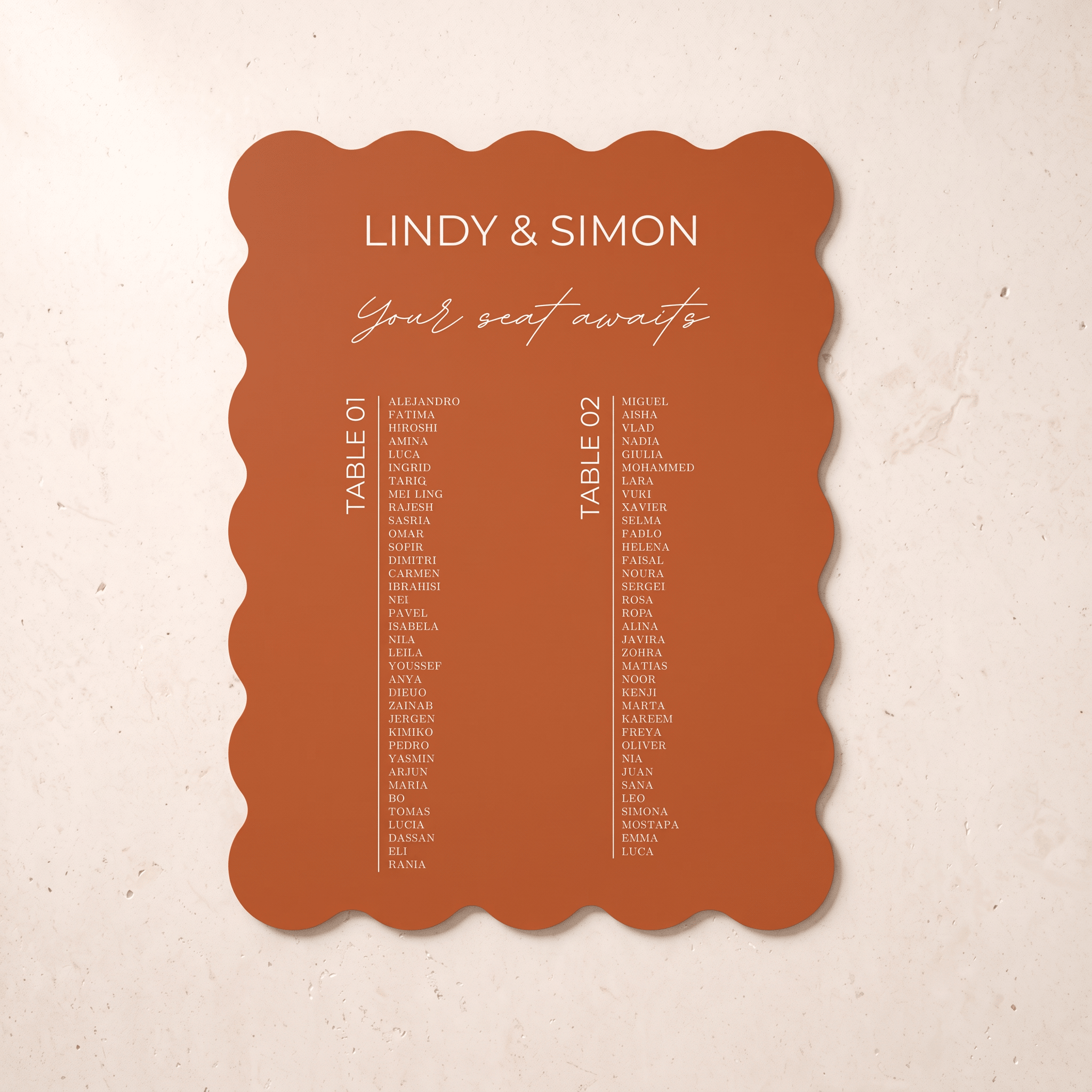 A scalloped terracotta orange wedding seating card with white printed text, displayed flat against a textured beige background.