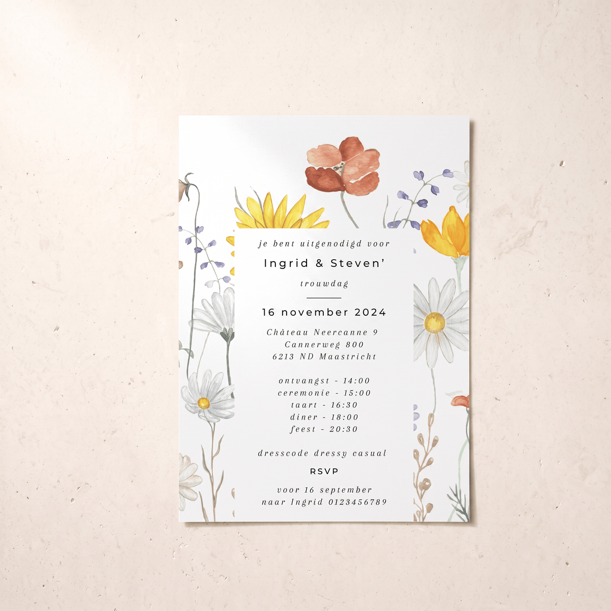 A vertical wedding invitation card with a white background and delicate watercolor floral illustrations in yellow, orange, blue, and white, placed on a textured beige surface.
