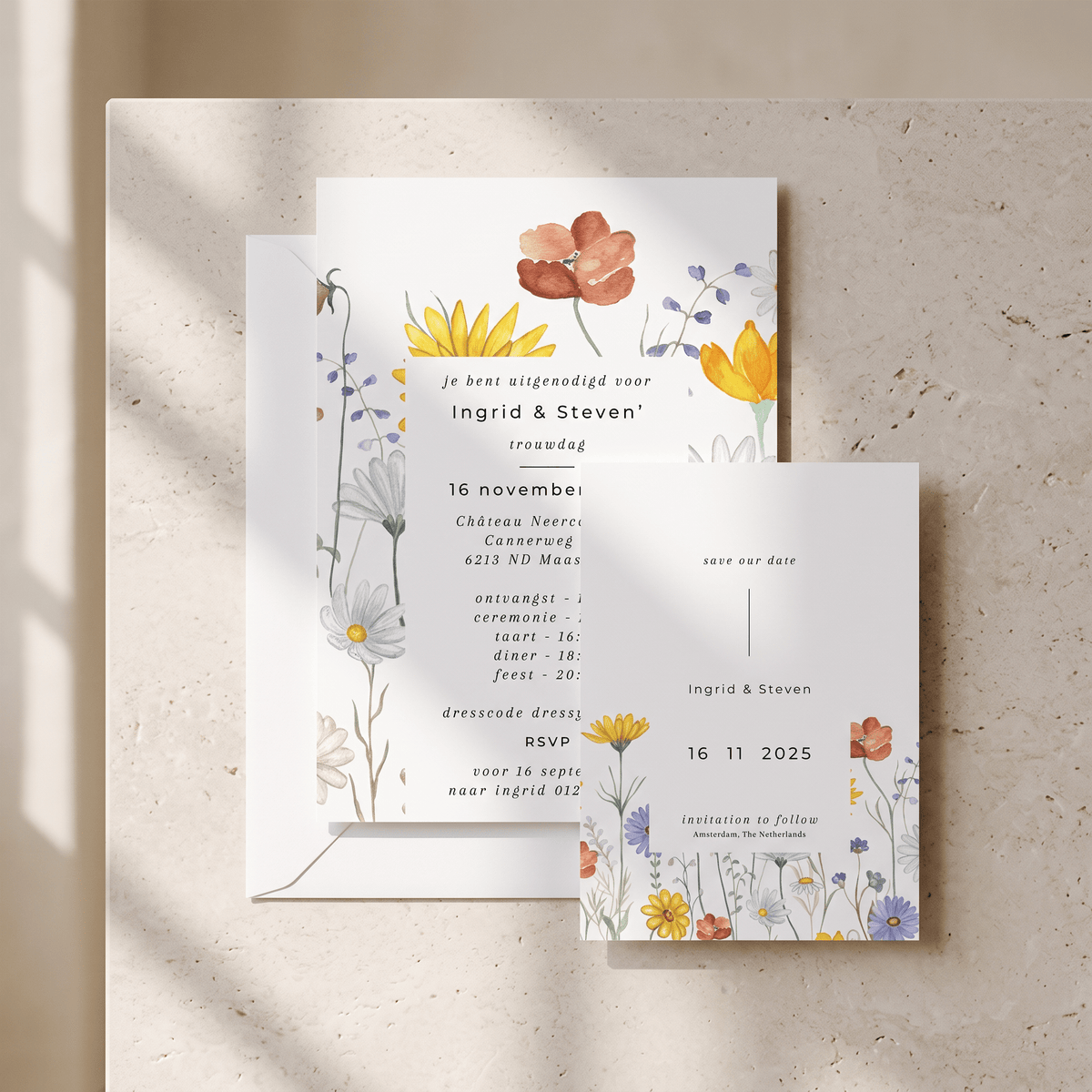 A floral wedding invitation suite styled on a textured beige stone surface with soft diagonal shadows. The set includes a main invitation card, a separate RSVP card, and an envelope, all decorated with delicate watercolor-style flowers in yellow, orange, blue, and purple tones.