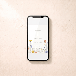 A black smartphone lying on a light beige textured surface, displaying a floral save-the-date card design with the names Ingrid & Steven and the date 16.11.