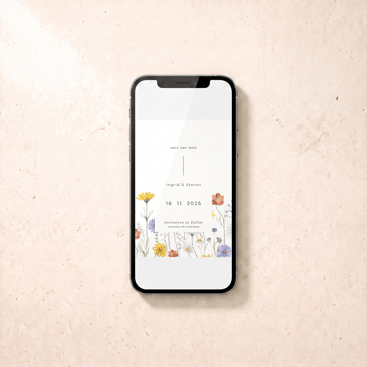 A black smartphone lying on a light beige textured surface, displaying a floral save-the-date card design with the names Ingrid & Steven and the date 16.11.