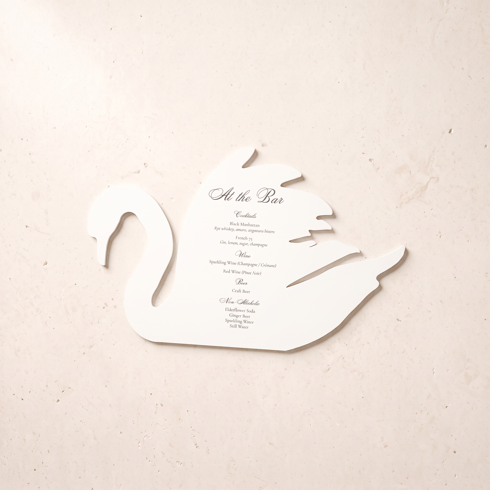 A swan-shaped white foambord wedding bar sign with printed bar list text, displayed on a textured beige surface.