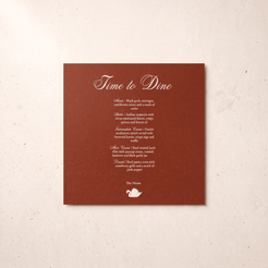 A square brown printed card with elegant white script and menu-style text reading 'Time to Dine' and a small teapot logo, photographed against a light beige textured background.