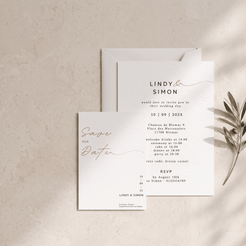 A wedding save-the-date card and matching invitation envelope arranged on a light beige textured surface with a small olive branch prop. The cards are white with black serif and script text and rose-gold cursive accents.