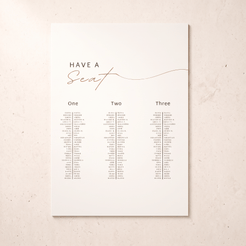 A vertical wedding seating chart print with the text 'HAVE A Seat' in black and rose-gold script, plus three columns labeled One, Two, and Three with small printed names beneath, shown on a light warm beige background.