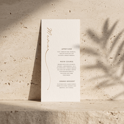 A tall, narrow wedding program or menu card with elegant typography, standing upright on a textured stone surface with soft shadow overlays.